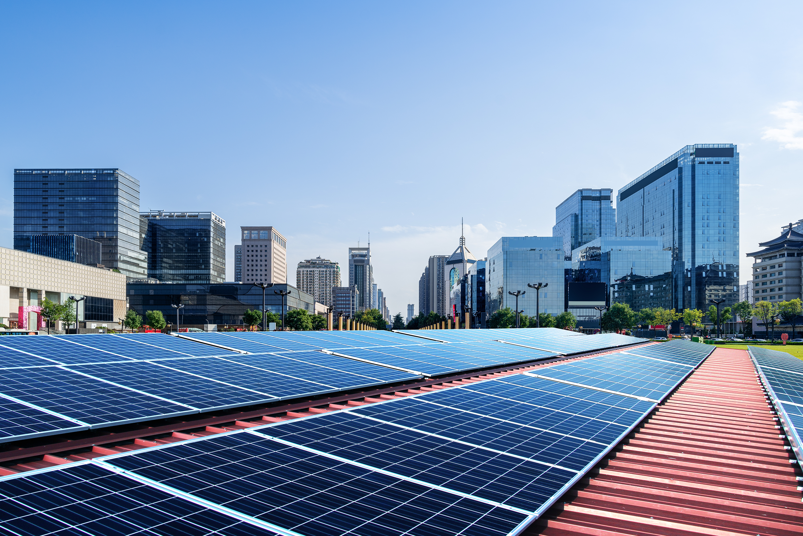 Solar panels in a ground while there are big buildings behind it